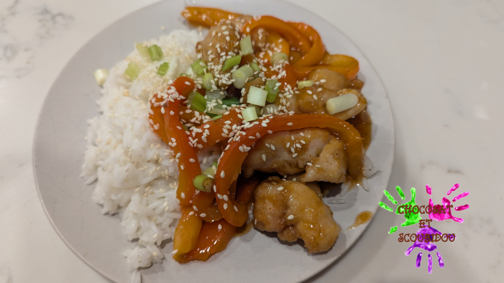 Assiette de Poulet Général Tao, poivrons rouges et riz, parsemé d'oignons verts et de graines de sésame